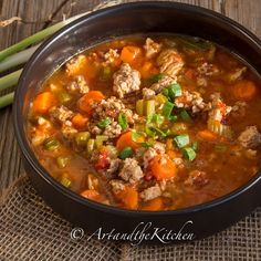 a black bowl filled with meat and vegetables