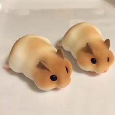 two small toy hamsters sitting on top of a table