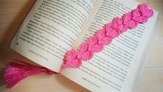 an open book with pink crocheted ribbon on it