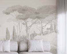 a white couch sitting in front of a wall with trees painted on it's side