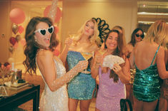 three women in sequin dresses holding up cards and wine glasses while standing next to each other