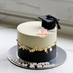 a white and black graduation cake with gold accents