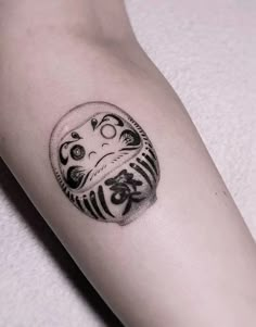 a small tattoo on the arm of a person with an owl and japanese symbols in it