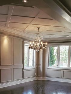 an empty room with wood floors and chandelier