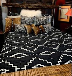 a bed with black and white comforter, pillows and blankets on top of it