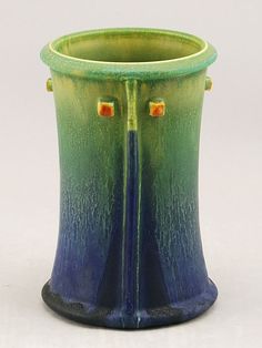 a green and blue vase sitting on top of a table