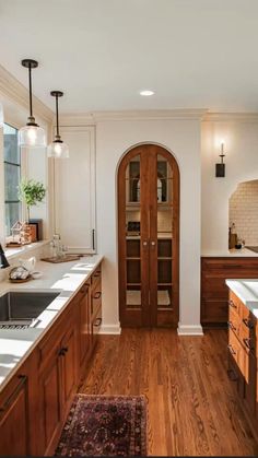 a kitchen with wooden cabinets and white counter tops next to a large open doorway that leads into the dining room