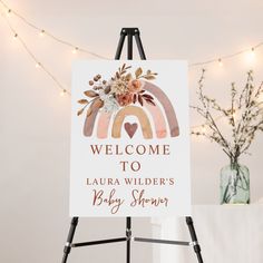 a welcome sign for a baby shower is displayed on a easel with lights in the background