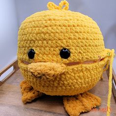 a crocheted yellow stuffed animal sitting on top of a wooden table