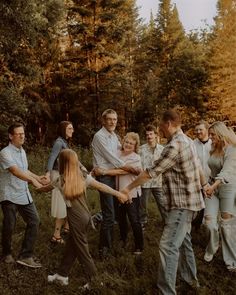 a group of people standing around each other in the grass with their arms extended and holding hands