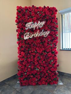 a large red flower wall with the words happy birthday written in white letters on it