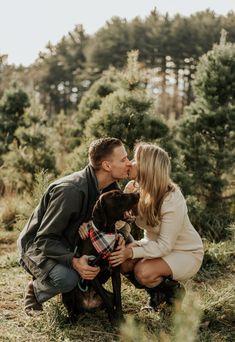 a man and woman kissing their dog in the woods