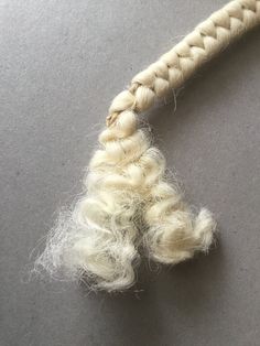 a piece of white wool is tied up to a rope on a gray table top