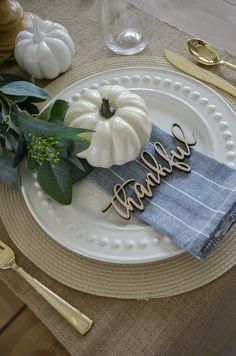 a white plate topped with a wooden name on top of a table next to gold utensils