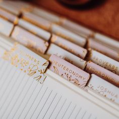 several pens are lined up next to each other on top of a book with gold lettering