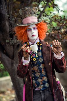 a man with red hair wearing a top hat and holding a cup in his hand