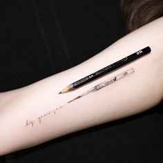 a pencil with writing on it is next to a tattoo