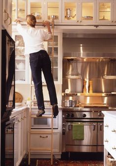 a man standing on a ladder in a kitchen