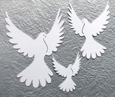 two white doves cut out from paper on a metallic surface with one bird facing the other