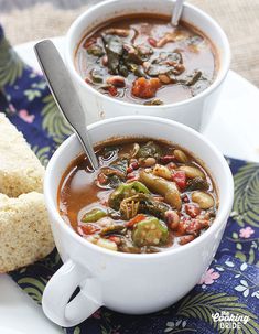 two white bowls filled with soup and bread on top of a blue table cloth next to each other