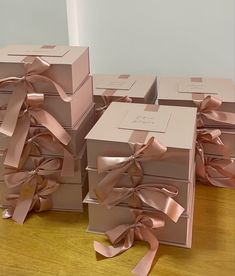 several boxes with pink bows on them sitting on a wooden table next to each other