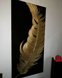 a large golden feather on a black and white wall