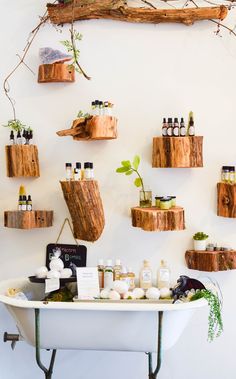 a bathtub filled with lots of bottles and soaps next to a tree branch