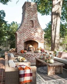 an outdoor fireplace with couches and tables in front of it, surrounded by trees