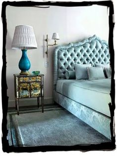 a bedroom with a bed, nightstand and lamp on the side table in front of it