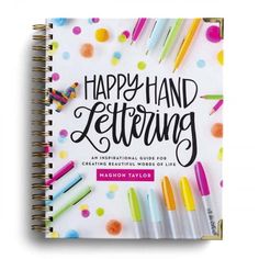 the happy hand lettering book with markers and crayons on it, surrounded by confetti