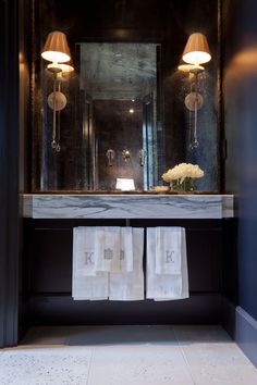 a bathroom sink with two towels hanging from it's side and a large mirror above it