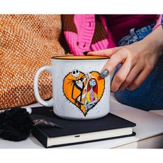 a person is holding a coffee mug with the image of jack and sally on it