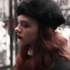 a woman with red hair wearing a black hat