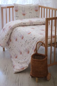 a baby crib next to a bed with a basket on the floor in front of it