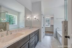 a large bathroom with double sinks, mirrors and bathtub in the middle of it