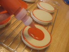 an orange and white doughnut on a rack with icing being poured onto it