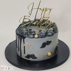 a birthday cake decorated with black and gold frosting on top of a metal plate