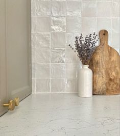 a wooden cutting board sitting on top of a counter next to a vase filled with flowers