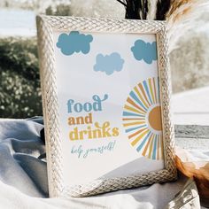 a sign that says food and drinks is on the table next to some feathers in front of it