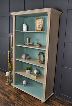 an empty bookcase in a room with wood flooring and walls painted teal