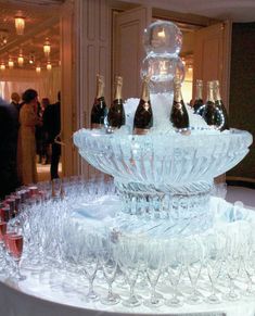 there are many wine glasses and bottles on the ice fountain that is filled with champagne