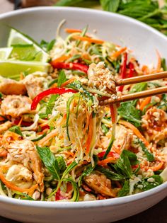 a white bowl filled with salad and chopsticks on top of the dish,