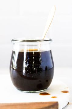 a glass jar filled with liquid sitting on top of a cutting board next to a wooden spoon