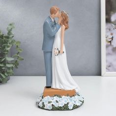 a figurine of a bride and groom kissing in front of a framed photo