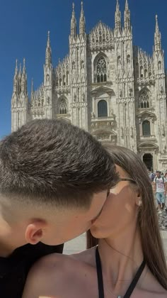 a man and woman kissing in front of a cathedral