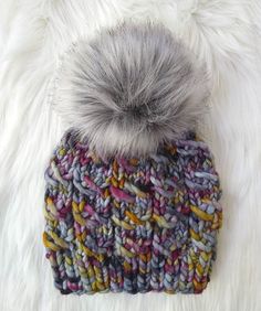 a multicolored knitted hat with a pom - pom on top