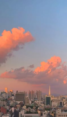 the city skyline is shown at sunset with pink clouds in the sky and buildings on either side