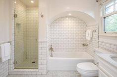 a white bathroom with a toilet, tub and shower