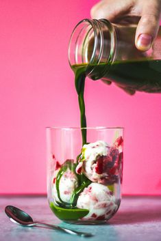 someone pouring green liquid into a glass filled with food