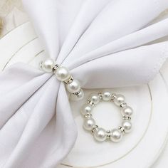 a white napkin with pearls on it and a silver beaded ring around the edge